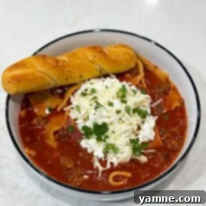 Slow cooker lasagna soup in bowl with spoon and herbs
