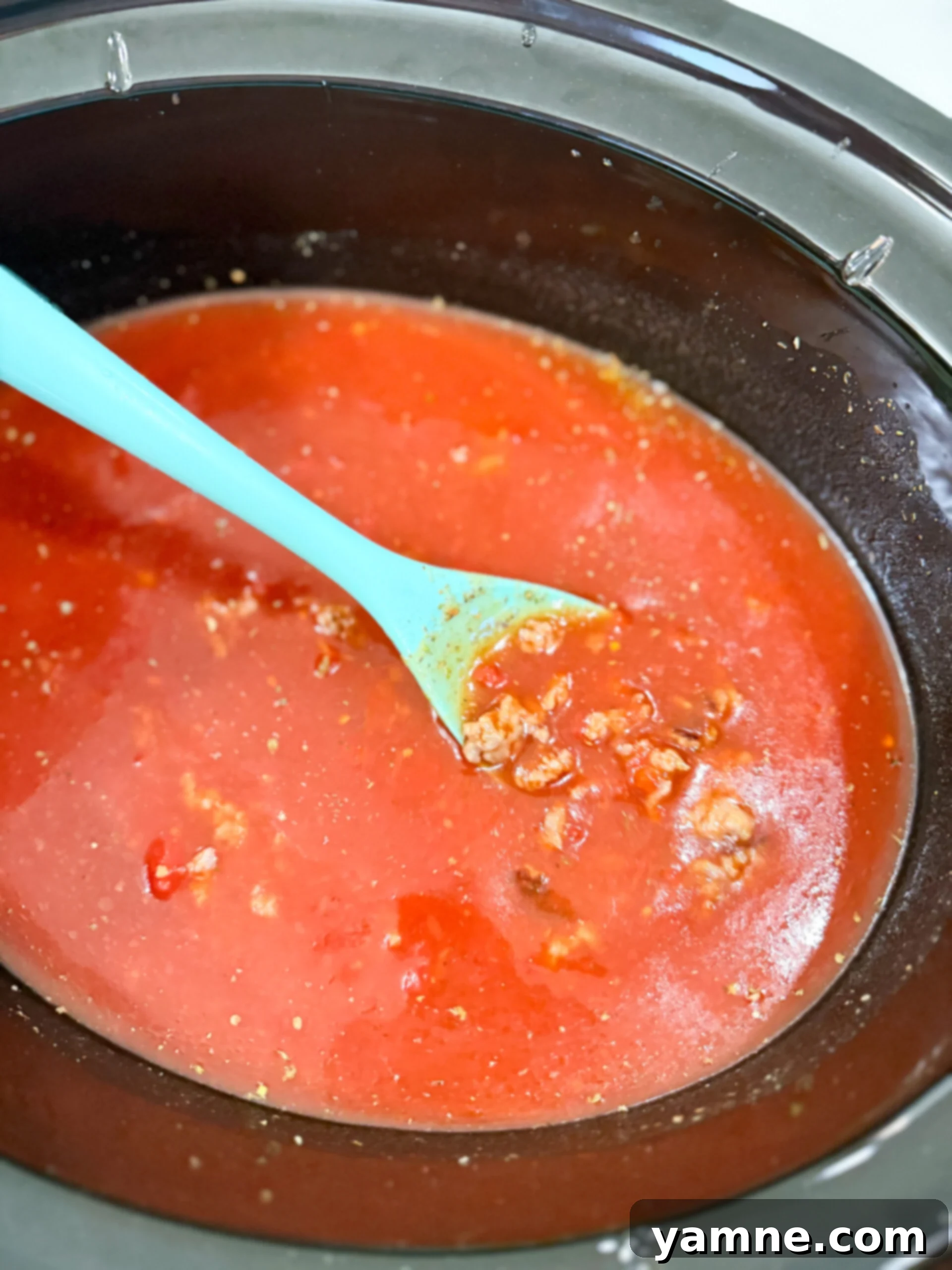 Adding ingredients to slow cooker for lasagna soup