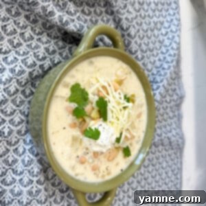 A top-down shot of Creamy White Chicken Chili in a bowl, garnished with cilantro and sour cream.