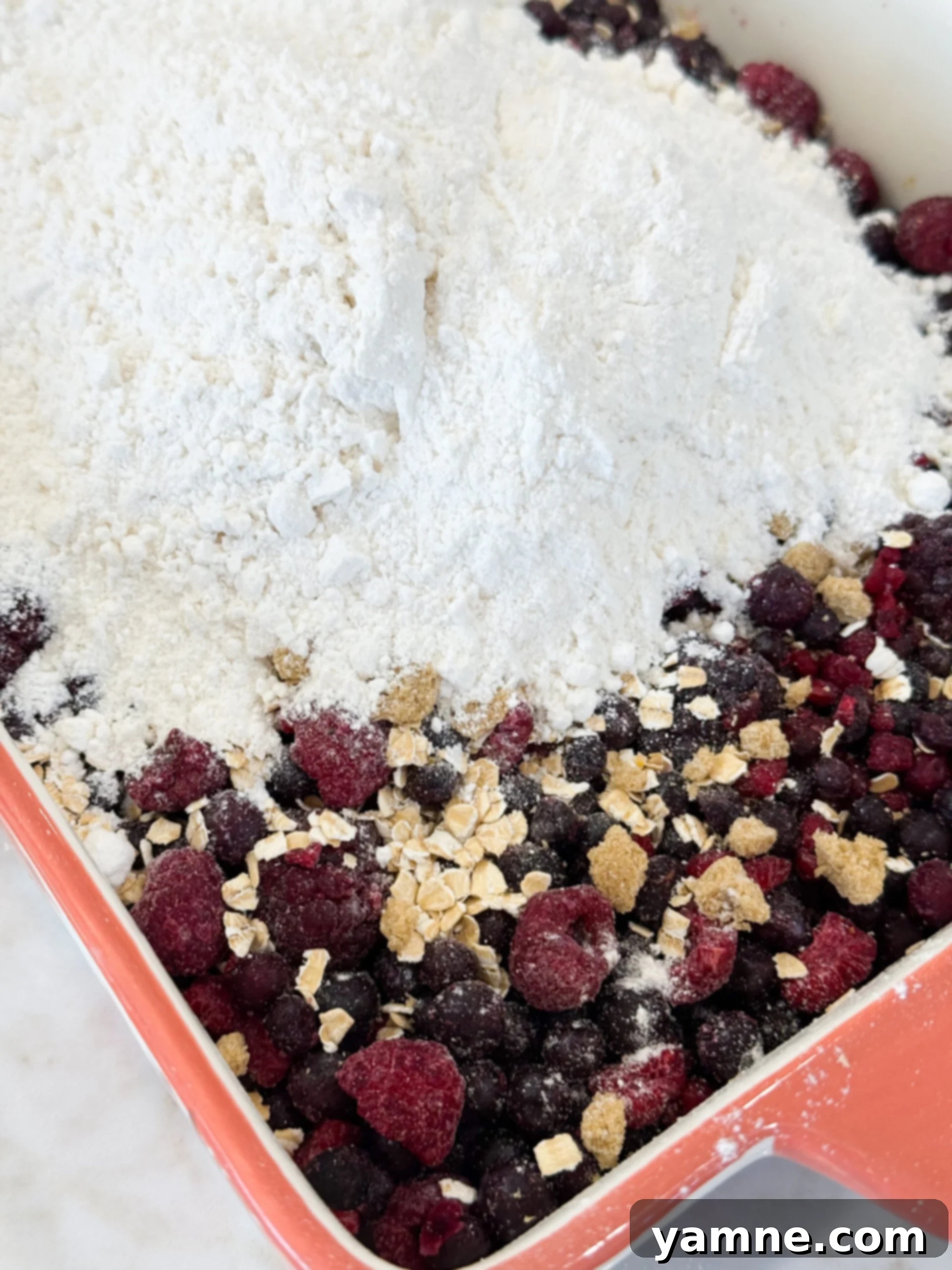 Layering berries, oats, and cake mix in baking dish