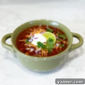 A bowl of hot One-Pot Taco Soup with a variety of toppings.