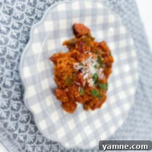 A vibrant dish of One-Pot Sausage and Rice garnished with fresh herbs, served in a skillet.