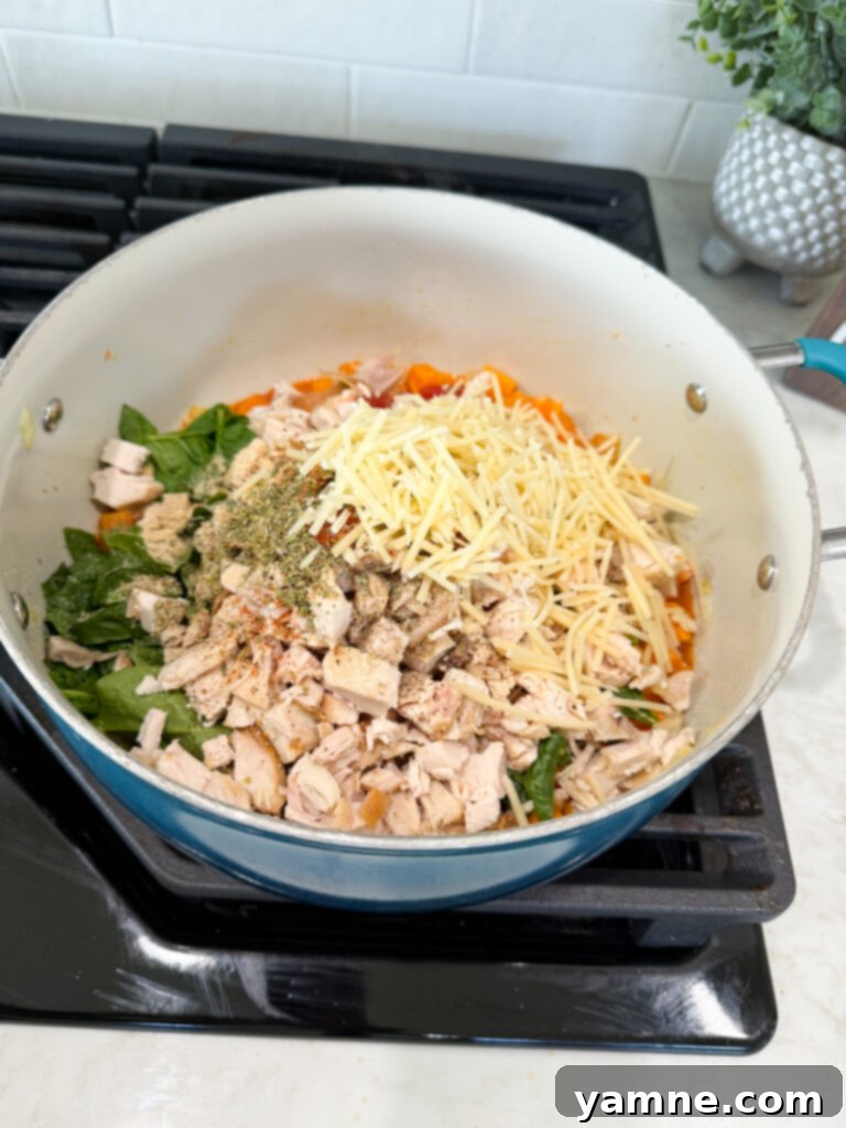 Finishing one-pan chicken and sweet potato dinner with spinach and tomatoes