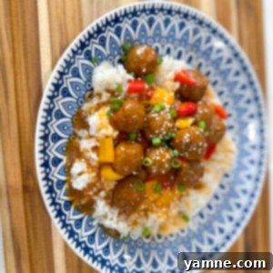 Delicious Sweet and Sour Meatballs coated in a sticky, tangy sauce, served over white rice with diced bell peppers.
