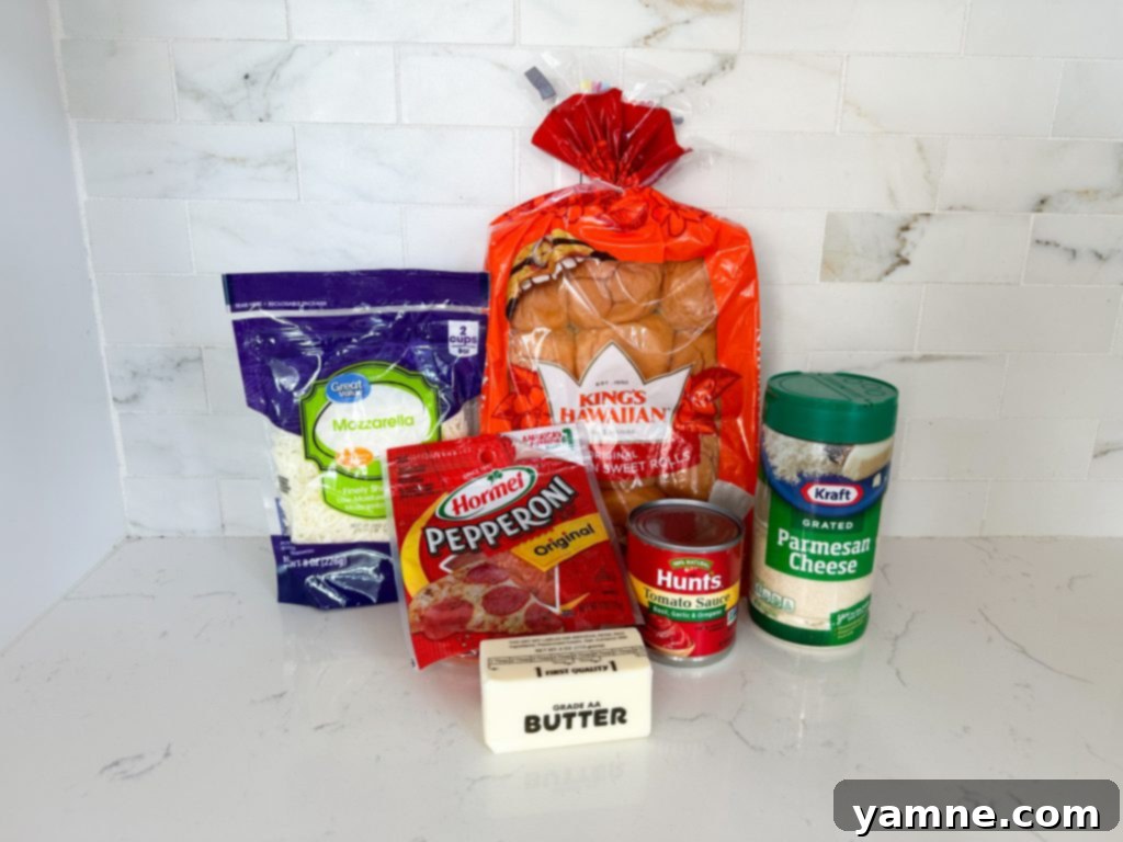 Ingredients for homemade pizza sliders laid out on a table, including Hawaiian rolls, cheese, pepperoni, and sauce.