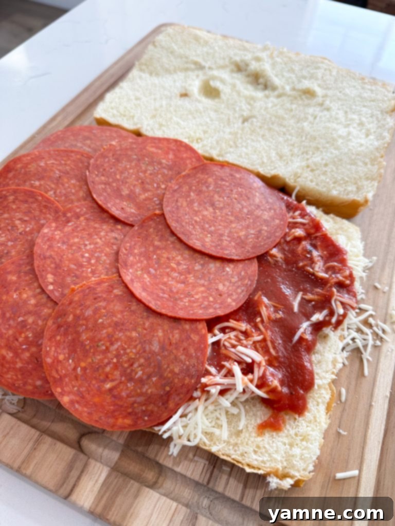 Hawaiian rolls sliced horizontally, with the bottom half placed in a baking dish, ready for pizza toppings.