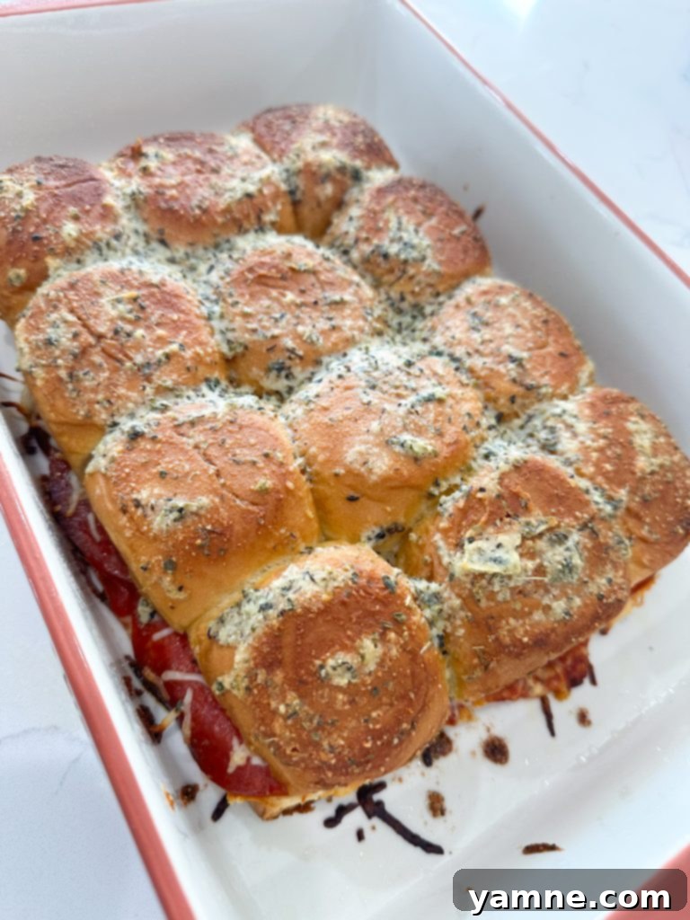 Pizza sliders brushed with a butter, Parmesan, and Italian seasoning mixture, ready for baking.