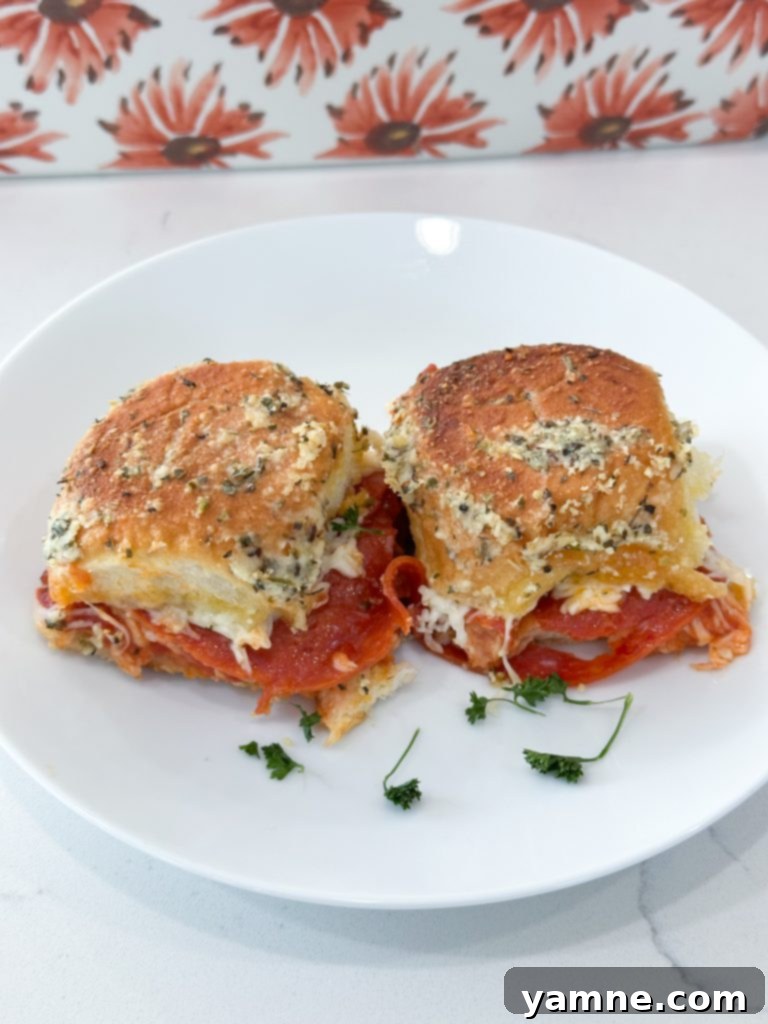 Close-up of baked pizza sliders, golden brown and cheesy, ready to be pulled apart and served.