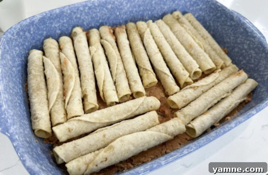 Spreading refried beans evenly on the bottom of a baking dish