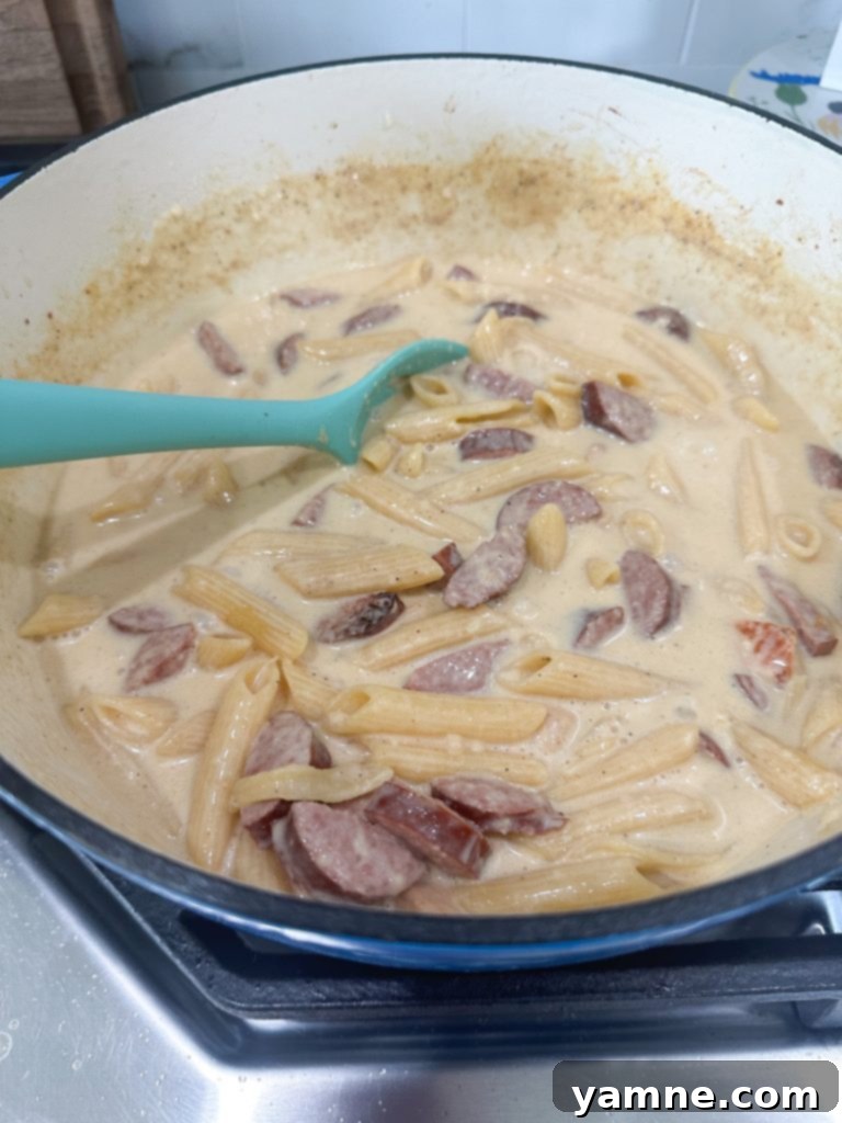 Adding broth and pasta to Cajun Chicken Alfredo