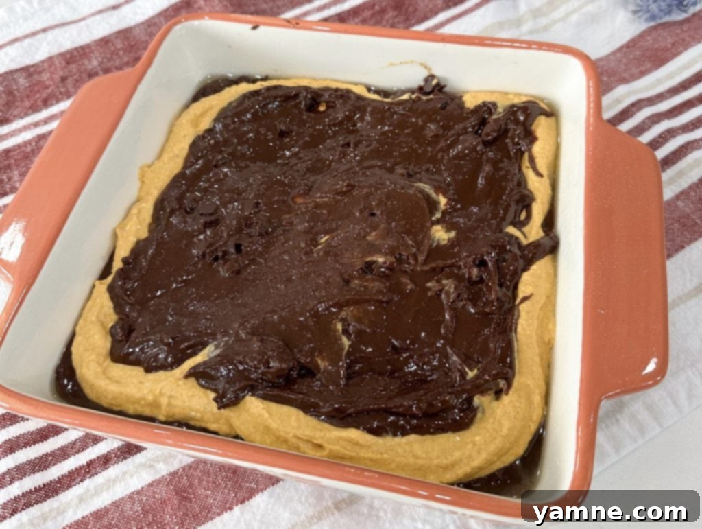 Swirled Pumpkin Cheesecake Brownies 8 Top layer of brownie batter spread over the pumpkin layer, ready for baking.