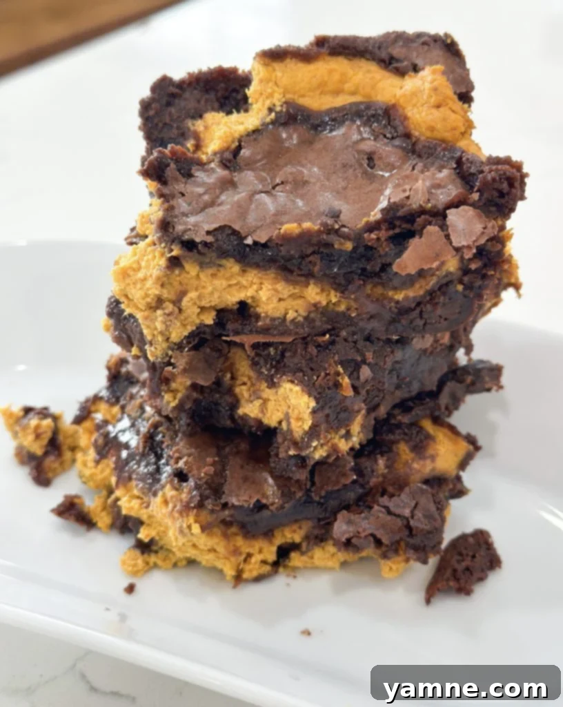 Swirled Pumpkin Cheesecake Brownies 9 Delicious pumpkin cheesecake brownies cut into squares, ready to be served.