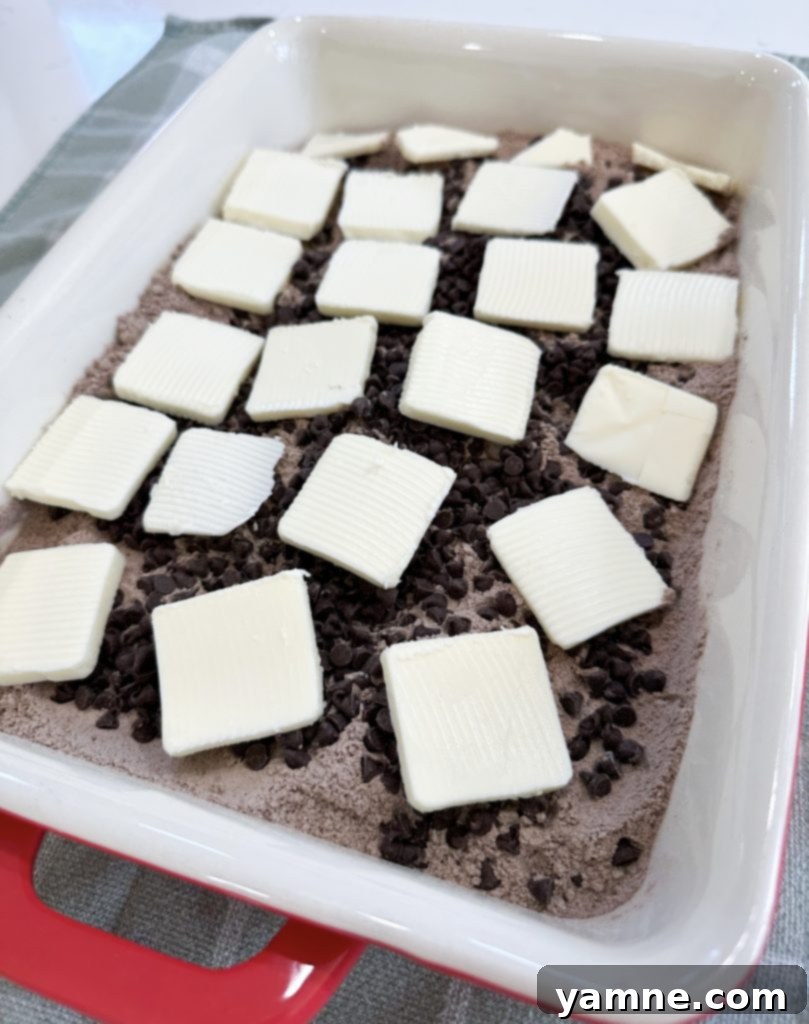 Thinly sliced butter arranged over the cake mix and chocolate chips