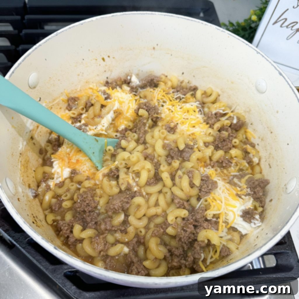 One-Pan Homemade Cheeseburger Pasta 5 Adding sauce, seasonings, pasta, and broth to hamburger helper