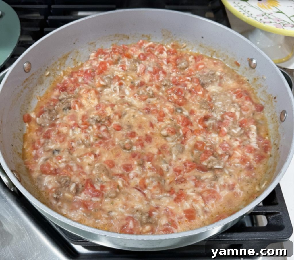 Close-up of browned ground beef in a large skillet, ready for the next steps of the casserole.