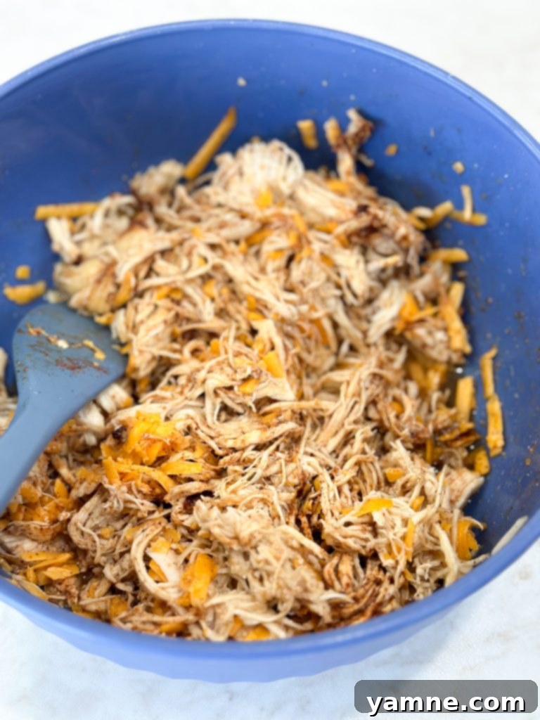 Honey-Glazed Lime Chicken Enchiladas 3 Shredded chicken being mixed with honey lime marinade in a bowl