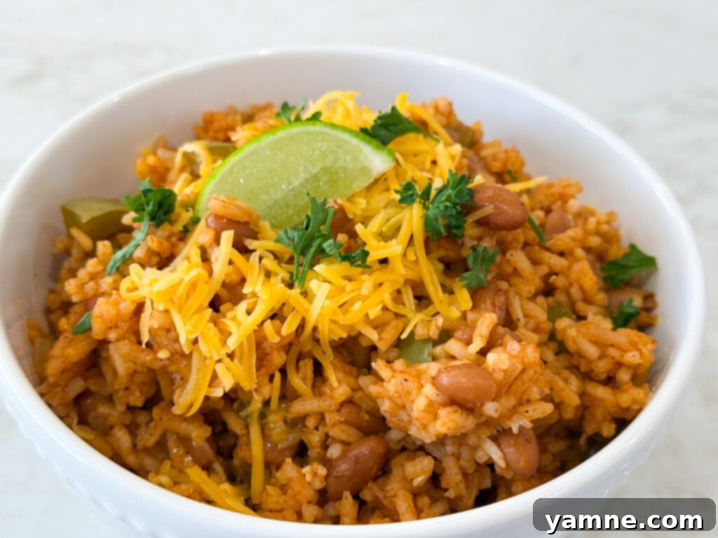 Close-up of a serving of Spanish rice with pinto beans, topped with melted cheese and fresh herbs.