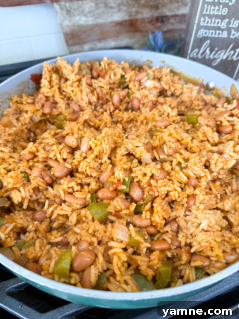A top-down shot of Spanish rice with pinto beans in a skillet, ready to serve.
