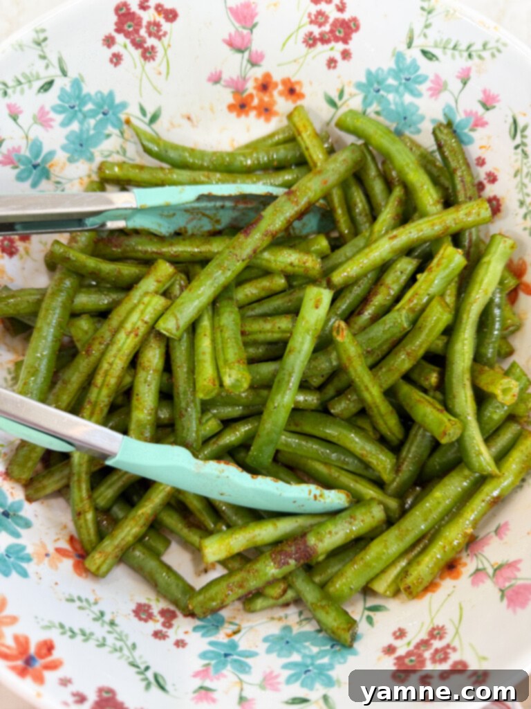 Green beans tossed with olive oil and spices on a sheet pan