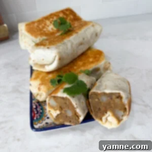 Hearty Lentil Potato Burritos 11 Lentil and potato burritos stacked neatly on a white plate, ready to be served.