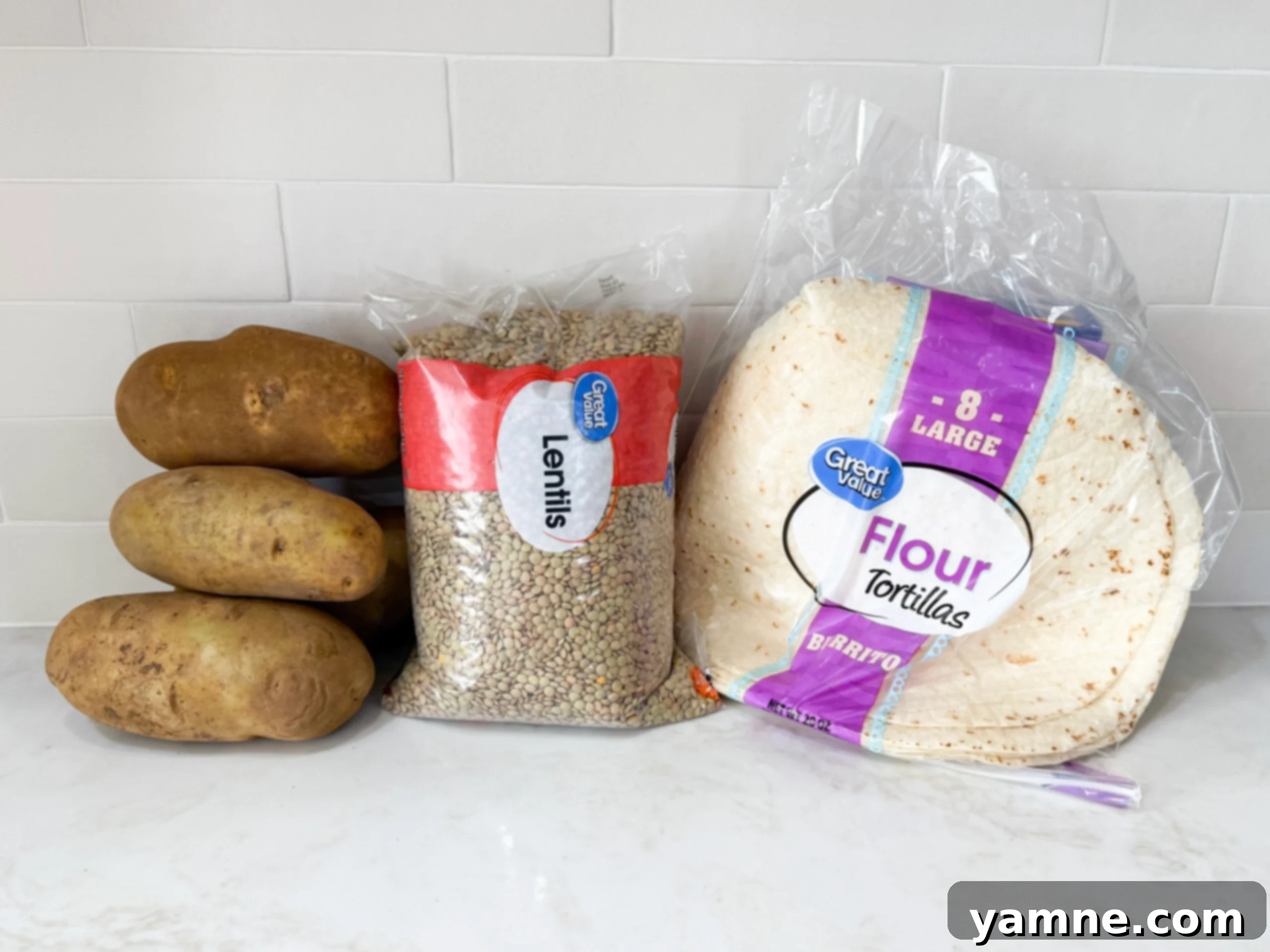 Hearty Lentil Potato Burritos 4 Fresh ingredients for lentil potato burrito wraps laid out on a kitchen countertop.