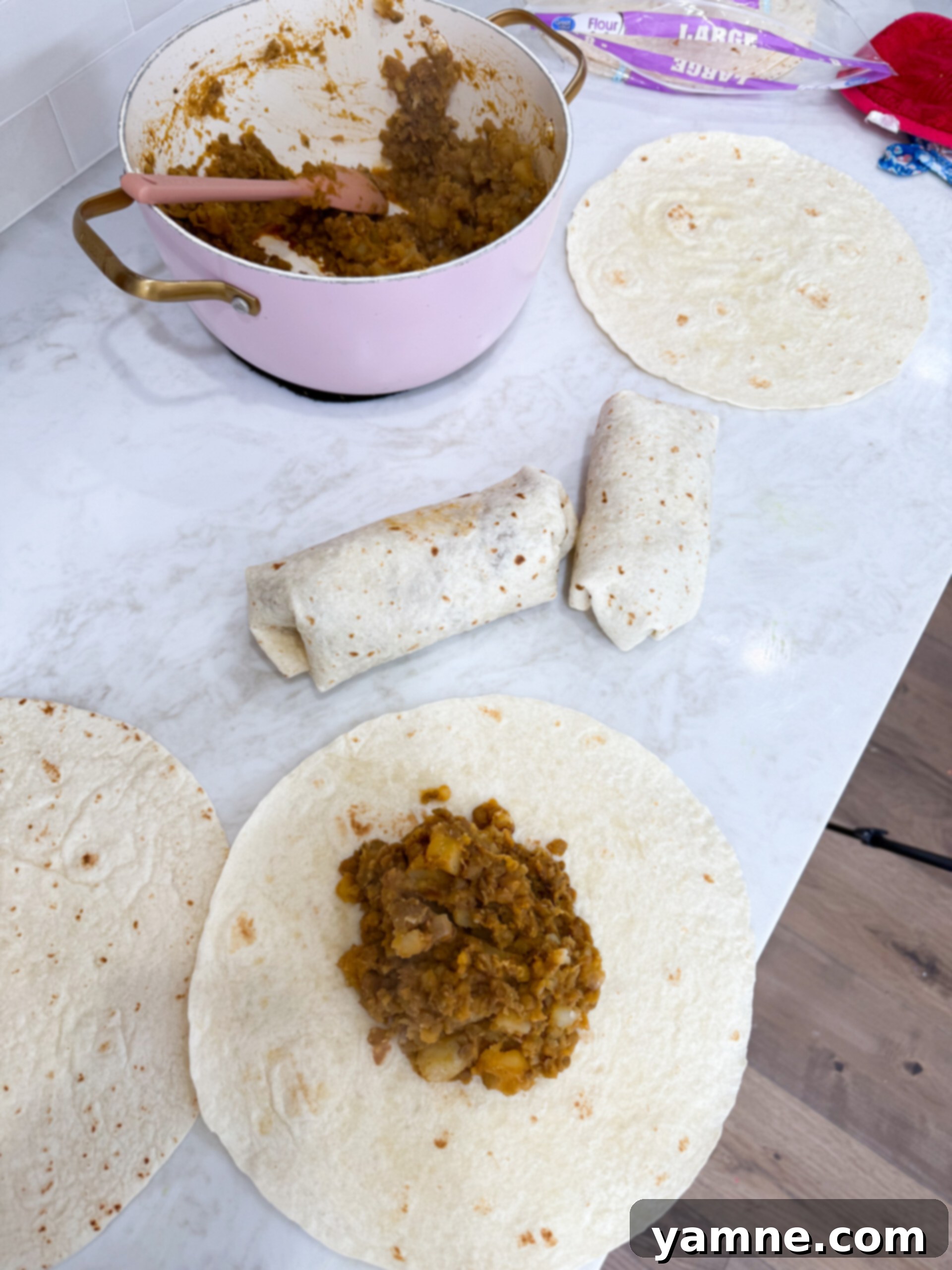 Hearty Lentil Potato Burritos 7 A warm flour tortilla being filled with the delicious lentil and potato mixture.