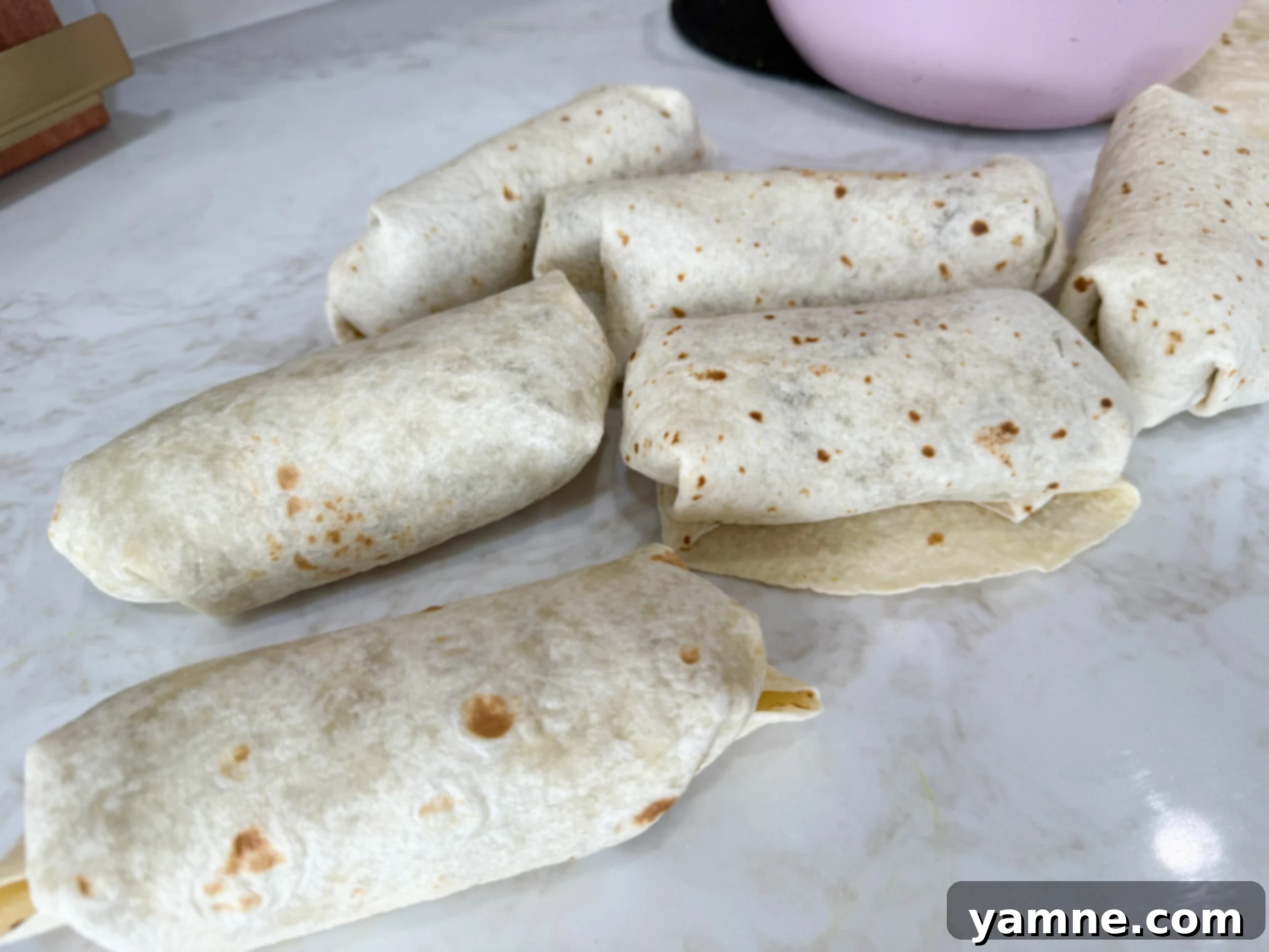 Hearty Lentil Potato Burritos 9 Several neatly rolled lentil and potato burritos on a kitchen counter, ready to be cooked or stored.