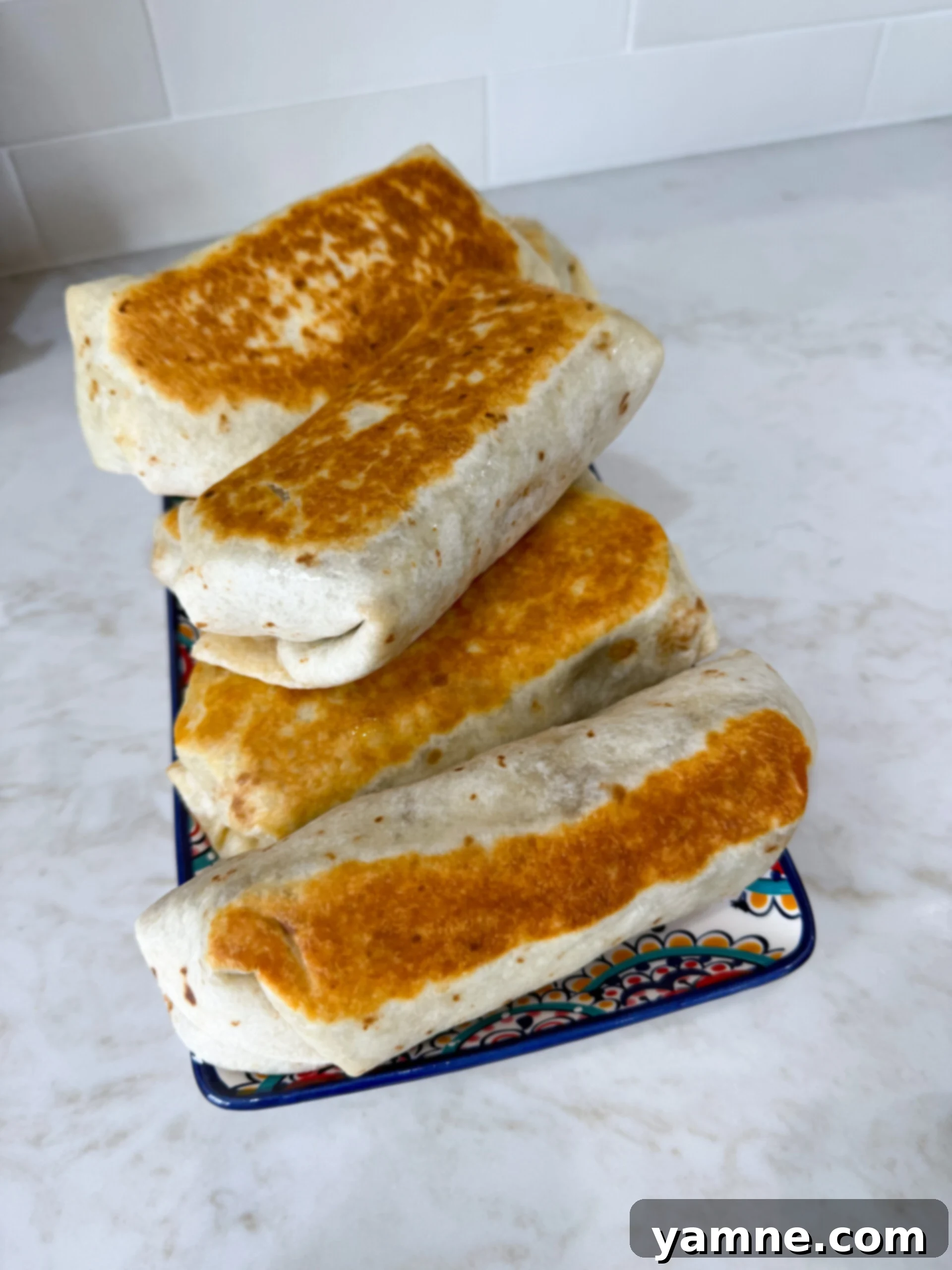 Hearty Lentil Potato Burritos 10 A single lentil potato burrito on a plate, garnished with fresh cilantro and a lime wedge.