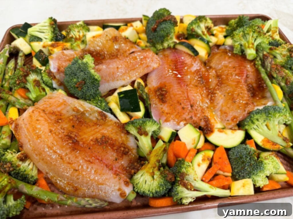 Easy One-Pan Tilapia Bake 4 Easy sheet pan tilapia arranged with vegetables on a baking sheet