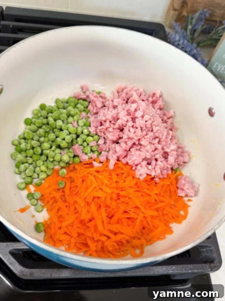 Adding peas, carrots, and ham to the pan