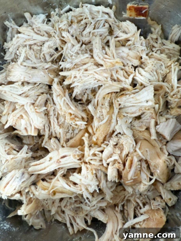 Close-up of shredded chicken in a slow cooker, mixed with its juices