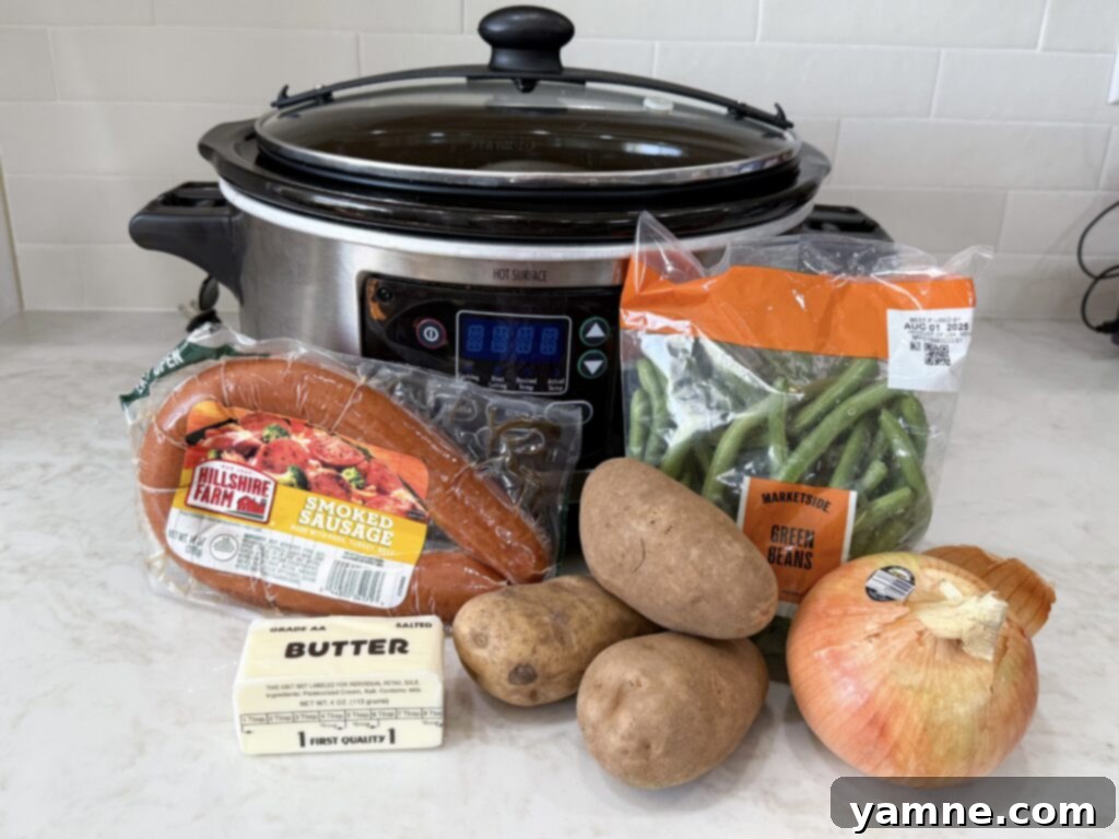 large black and grey slow cooker with sausage, green beans, onion, butter, and potatoes on a white counter