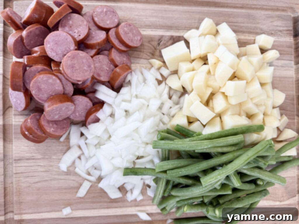 chopped sausage, diced onions and potatoes, and green beans on a cutting board