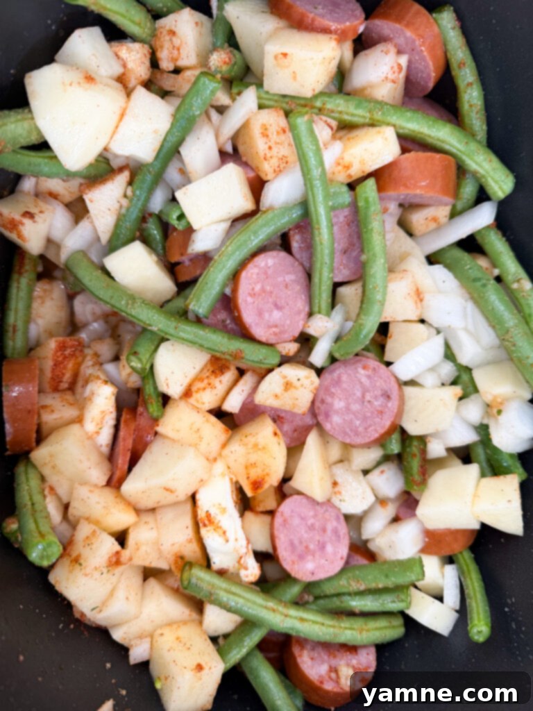 Prepared sausage, green beans, diced onions and potatoes in a slow cooker