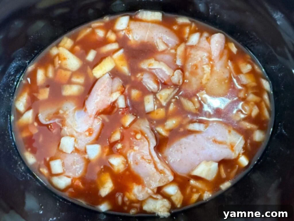 Raw chicken in Hawaiian sauce in a slow cooker