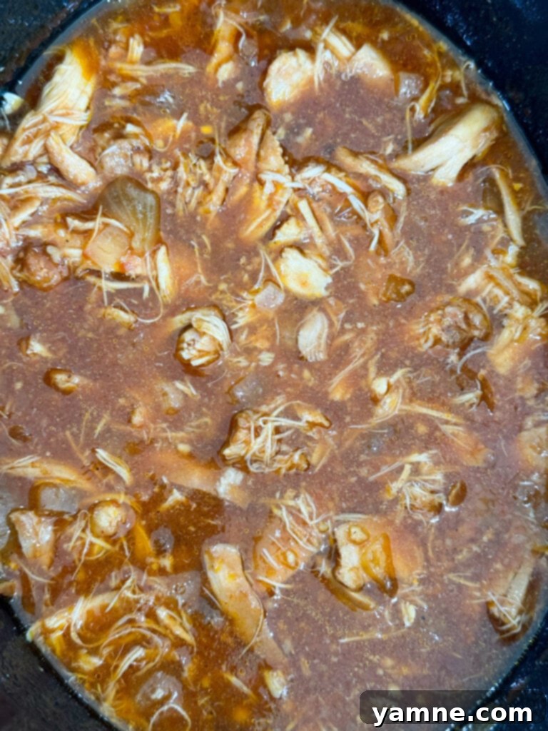 Cooked chicken coated in a rich, sweet Hawaiian sauce, ready to be shredded for sandwiches or served as a main dish.