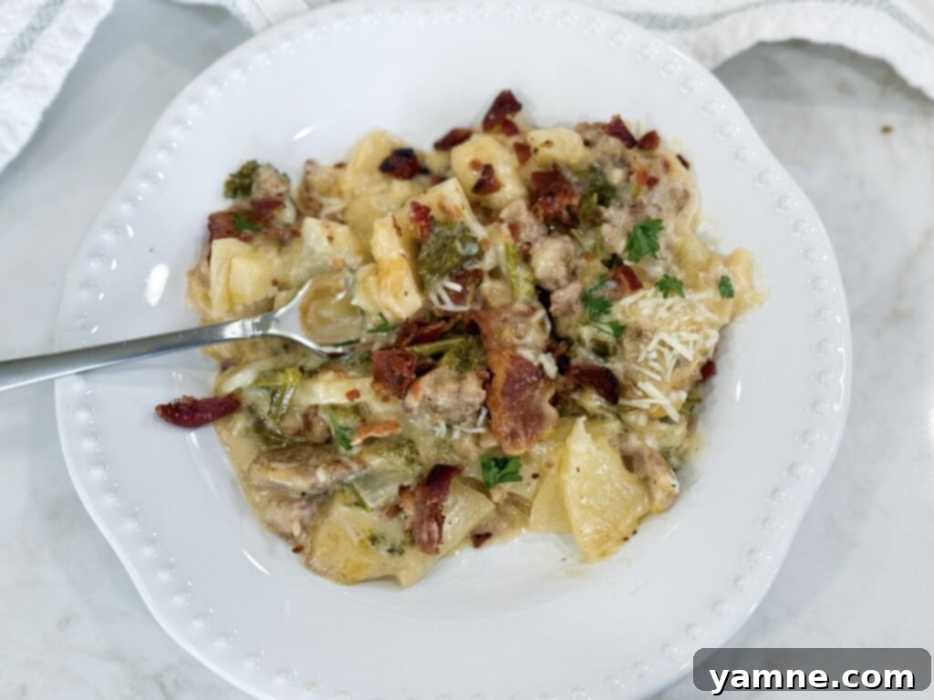 Creamy Zuppa Toscana Sausage Potato and Kale Bake 12 A plated serving of Zuppa Toscana Casserole, showcasing the layers of tender potatoes, vibrant kale, savory sausage, and crispy bacon in a creamy sauce.