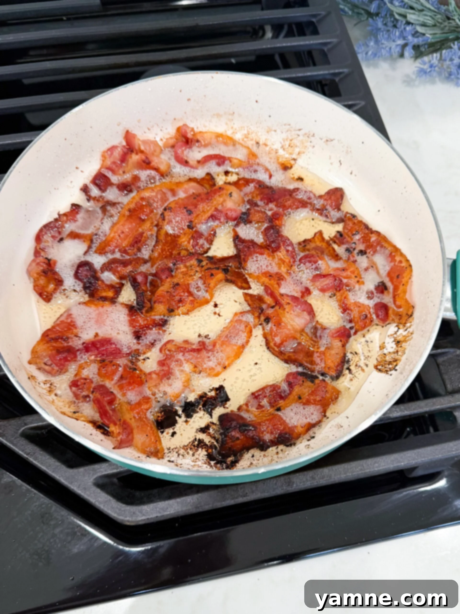 Creamy Zuppa Toscana Sausage Potato and Kale Bake 5 Crispy bacon pieces sizzling in hot grease in a pan, ready to be removed.