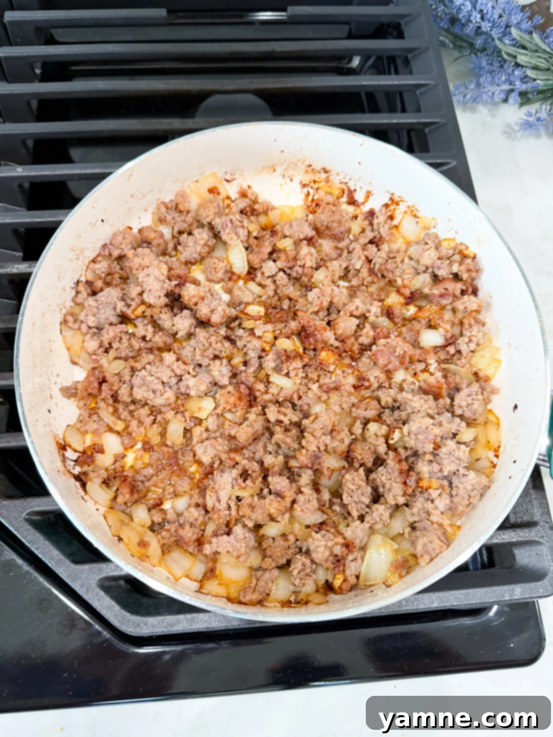Creamy Zuppa Toscana Sausage Potato and Kale Bake 6 Italian sausage and diced onions browning in a skillet with minced garlic.