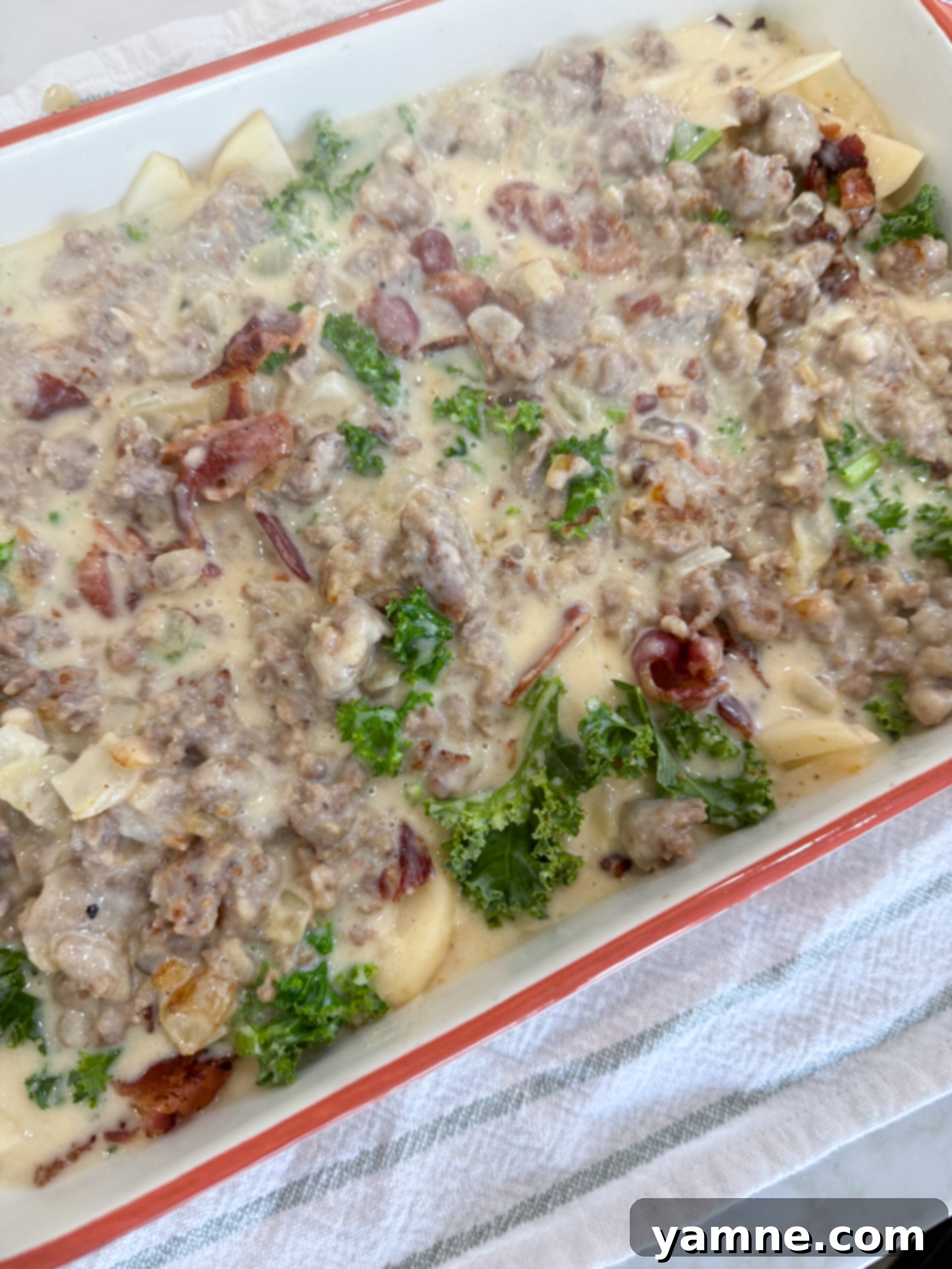 Creamy Zuppa Toscana Sausage Potato and Kale Bake 9 Zuppa Toscana Casserole layered with creamy sausage mixture and ready for Parmesan cheese before baking.