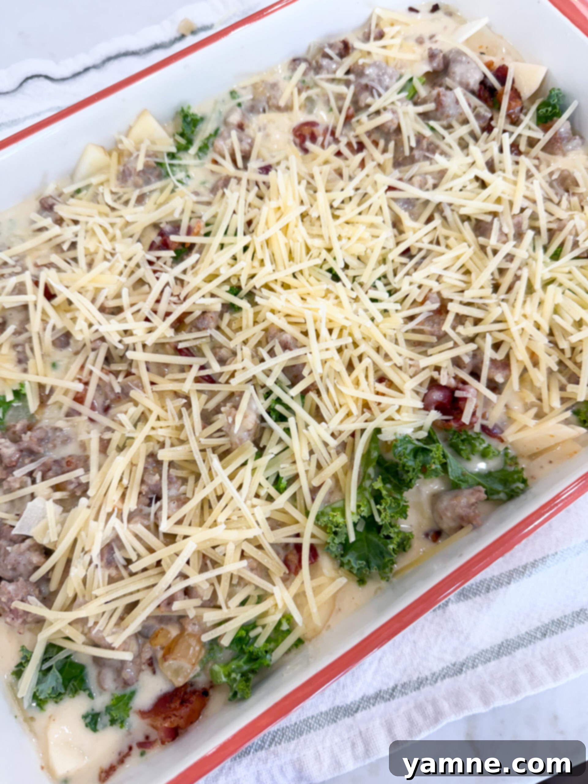 Creamy Zuppa Toscana Sausage Potato and Kale Bake 10 Zuppa Toscana Casserole topped with Parmesan cheese and covered with foil, ready to be baked.