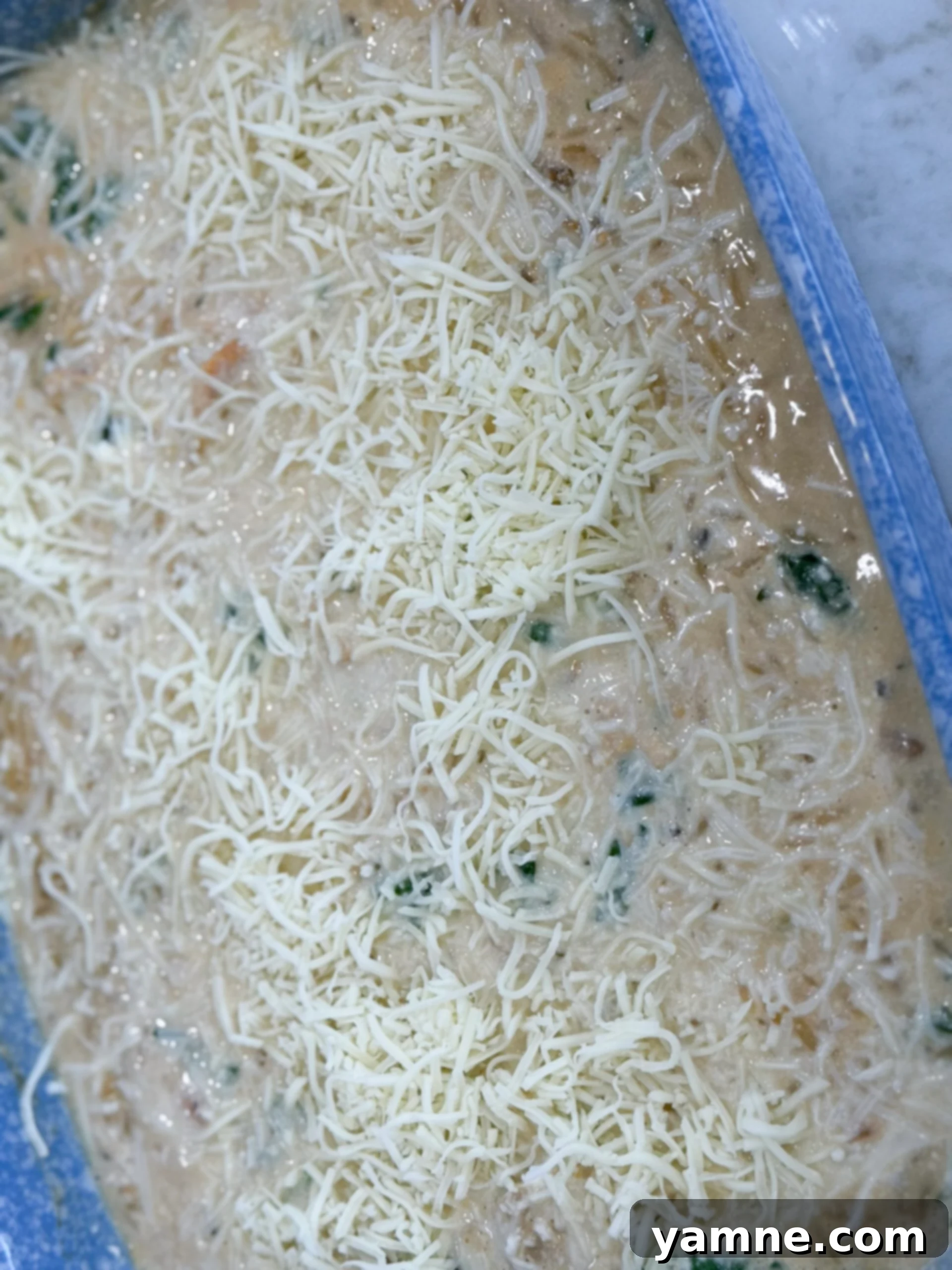 Adding mozzarella cheese to Spinach Chicken Orzo Casserole