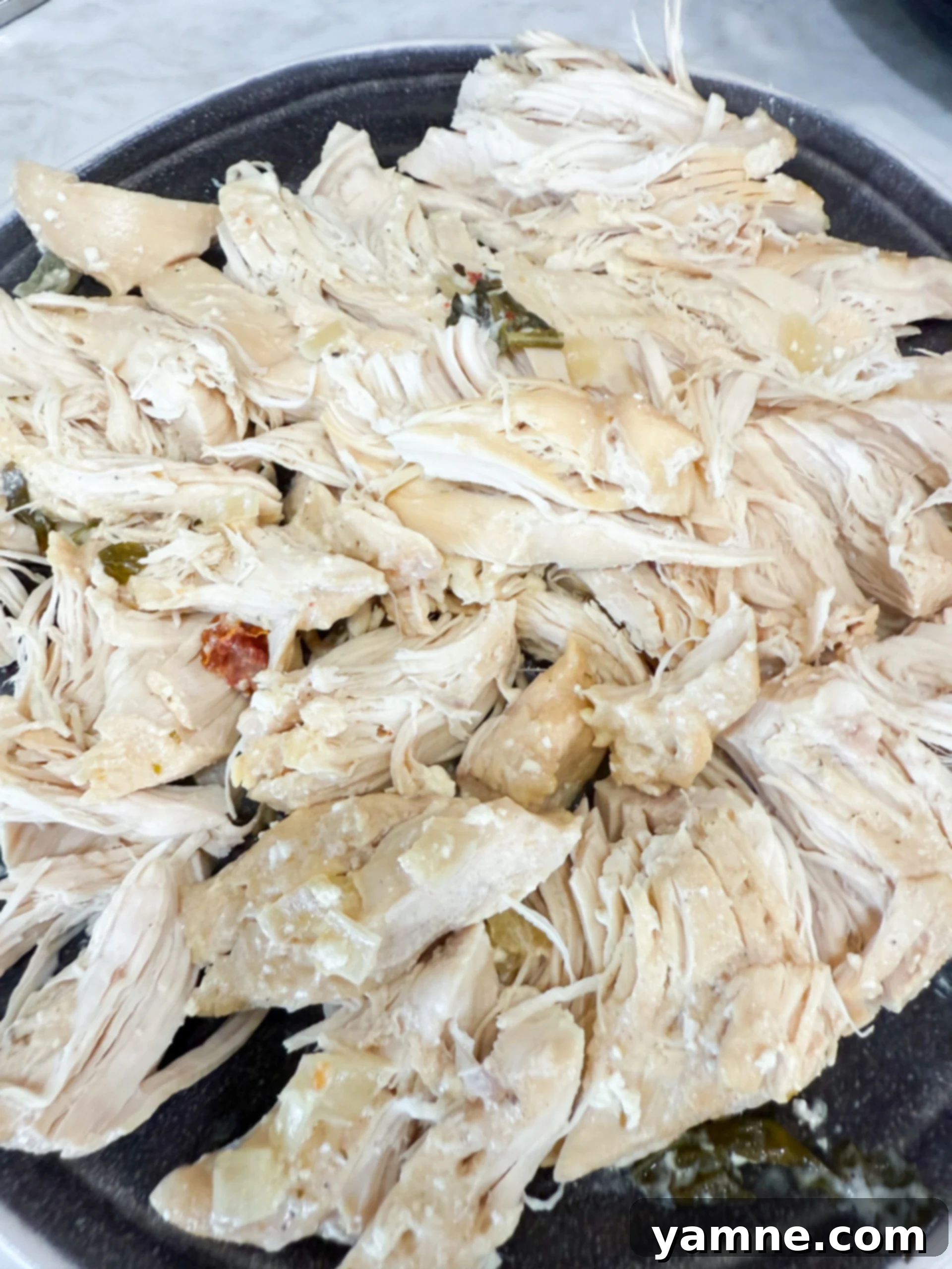 Perfectly shredded chicken on a cutting board, ready to be returned to the slow cooker.