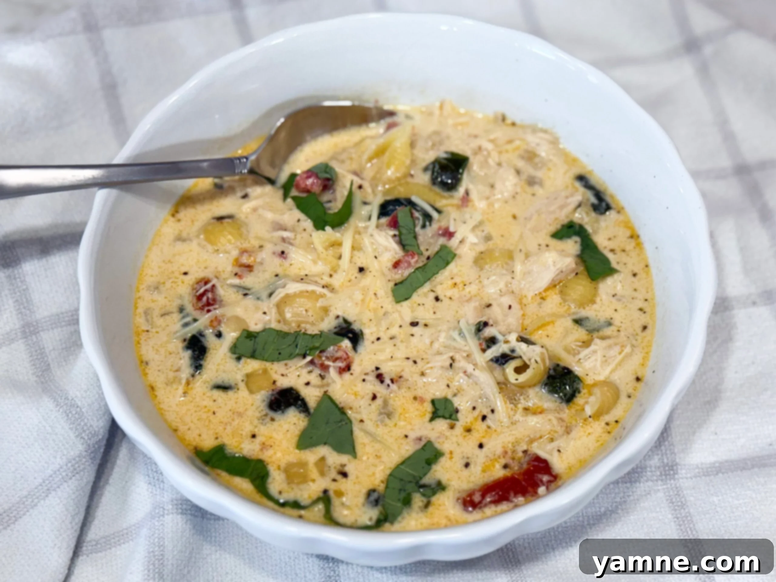 A bowl of Slow Cooker Marry Me Chicken Soup with pasta and spinach - creamy, cozy, and family-friendly!