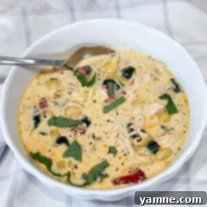 Bowl of creamy Slow Cooker Marry Me Chicken Soup with pasta, spinach, and sun-dried tomatoes