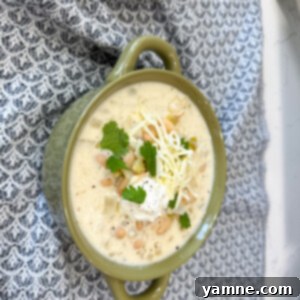 A comforting bowl of Slow Cooker White Chicken Chili, garnished with fresh cilantro and a swirl of sour cream.