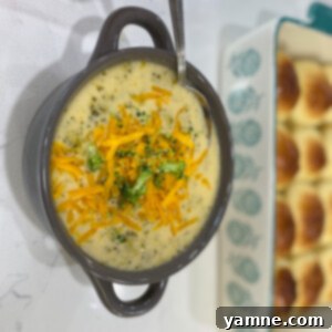 A rich bowl of Slow Cooker Broccoli Cheese Soup, with visible broccoli florets and a smooth, golden cheese broth.