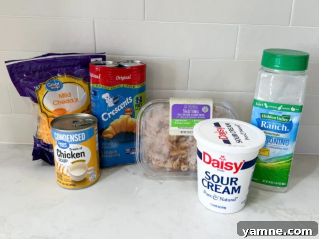 Flaky Cheesy Chicken and Broccoli Bake 4 A collection of fresh ingredients for cheesy chicken crescent roll casserole, including chicken, broccoli, crescent dough, soup, and cheese, neatly arranged on a kitchen counter, ready for preparation.
