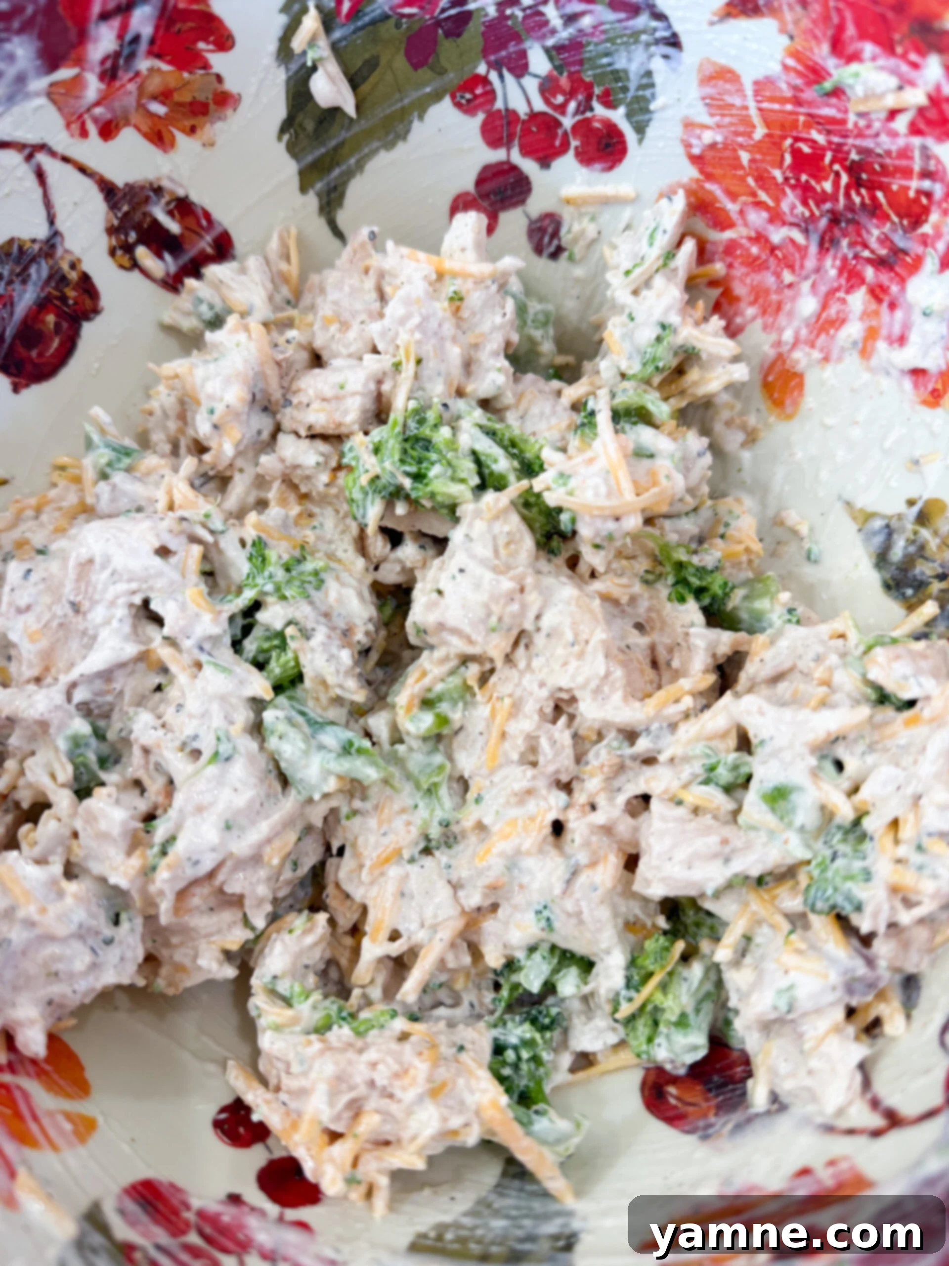 Flaky Cheesy Chicken and Broccoli Bake 5 Mixing chopped cooked chicken, sour cream, broccoli, ranch seasoning, and shredded cheddar cheese in a medium mixing bowl.
