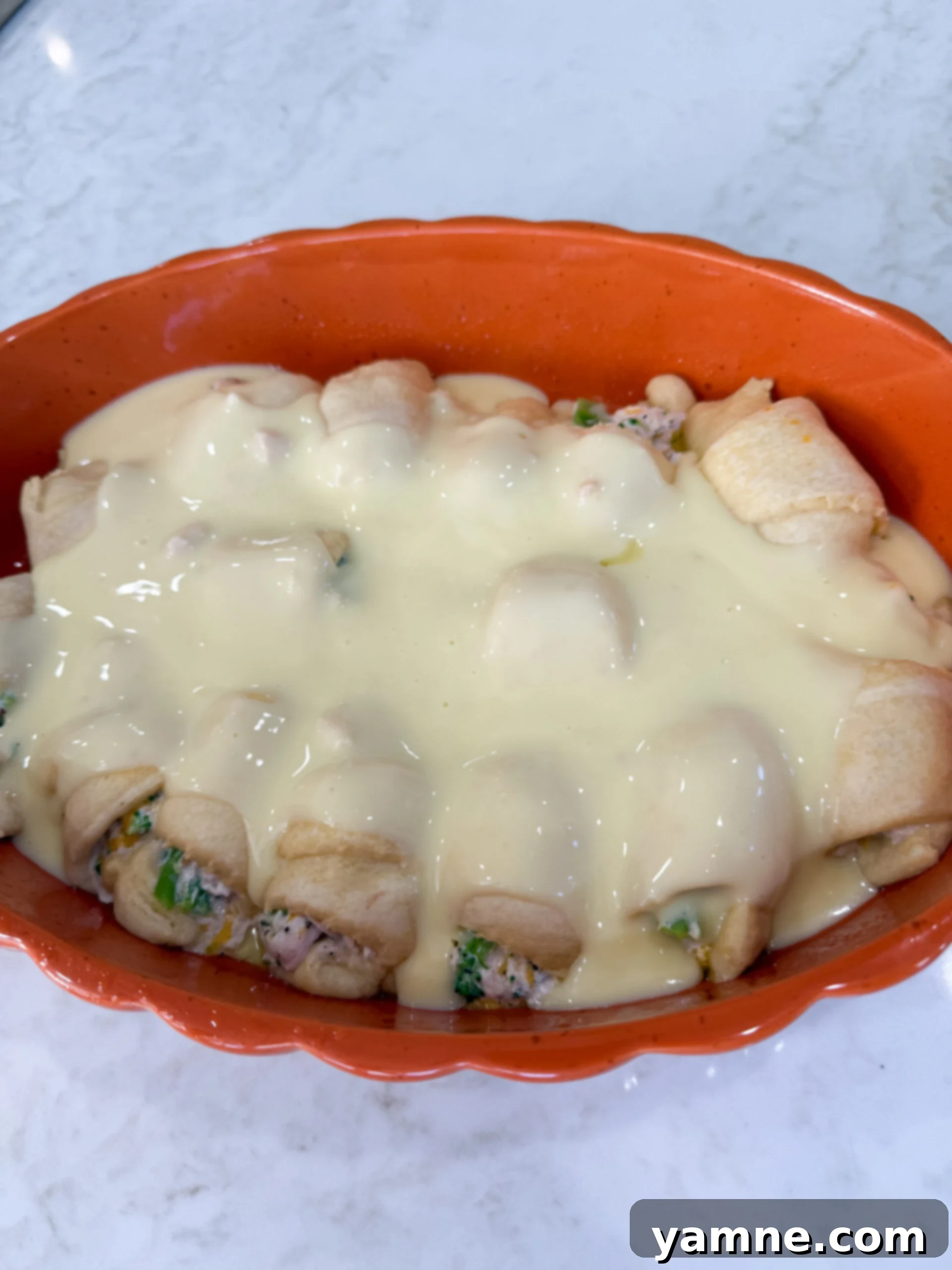 Flaky Cheesy Chicken and Broccoli Bake 9 Pouring the creamy chicken soup and milk mixture evenly over the partially baked crescent rolls in the baking dish, before adding the final cheese topping.